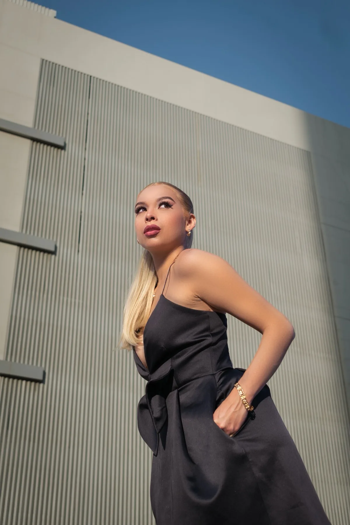 Fashion campaign photograph shot on location against Dubai's architecture, low angle against the sky